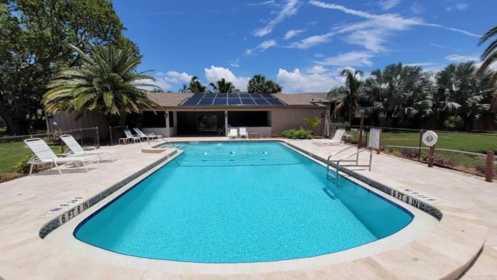 Backyard swimming pool with lounge chairs and solar panels on the home roof