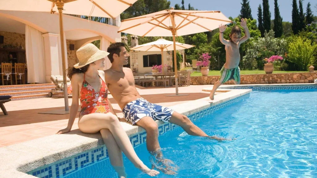 Family relaxing by a backyard swimming pool on a sunny day