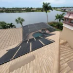 Solar pool heating panels installed on a residential roof overlooking water