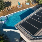 Solar pool heating panels installed beside a residential swimming pool
