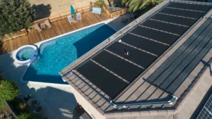 Solar pool heating panels installed on a roof overlooking a backyard pool