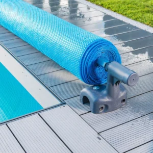 Solar pool cover rolled on a reel beside a residential swimming pool