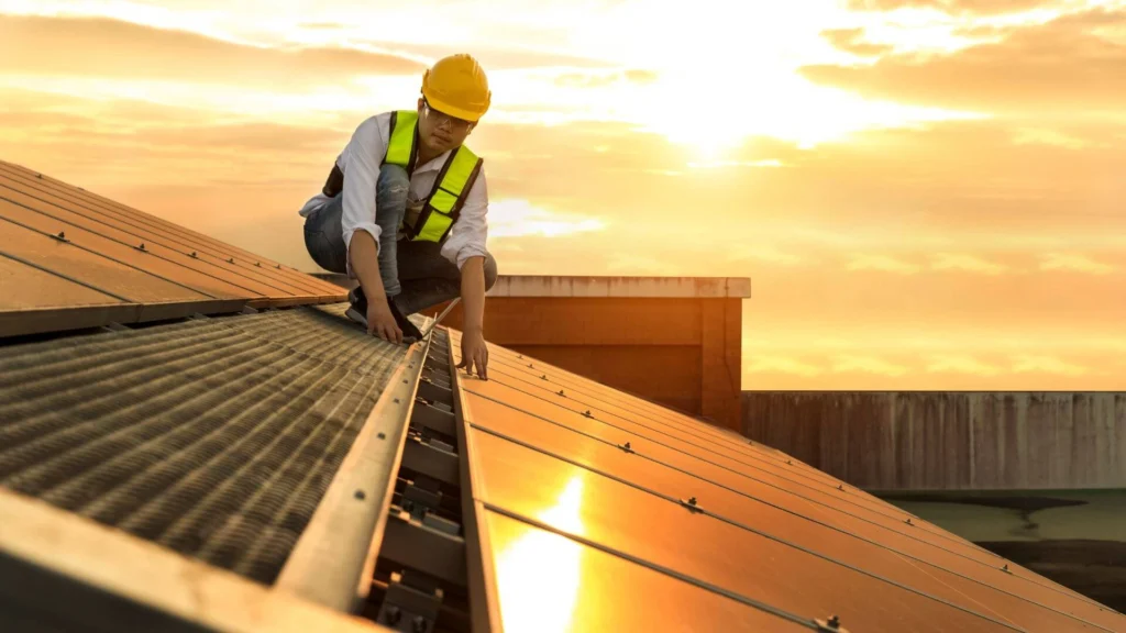 Technician working on solar panels installed on a residential roof at sunset