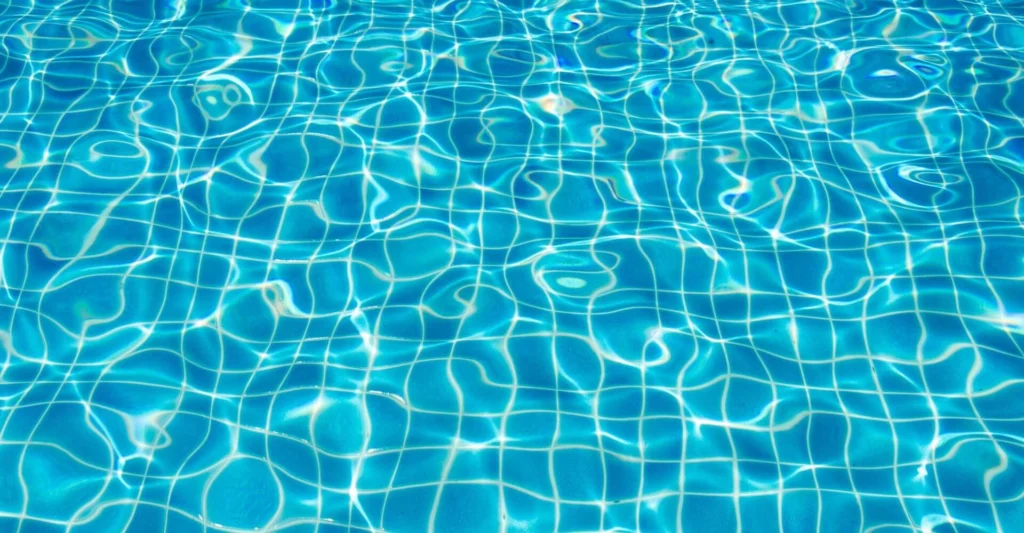 Clear blue swimming pool water with sunlight reflections