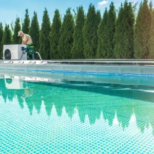 Technician working on pool equipment beside a backyard swimming pool