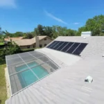 Solar panels installed on a roof overlooking a backyard pool