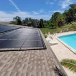 Solar pool heating panels installed beside a residential swimming pool
