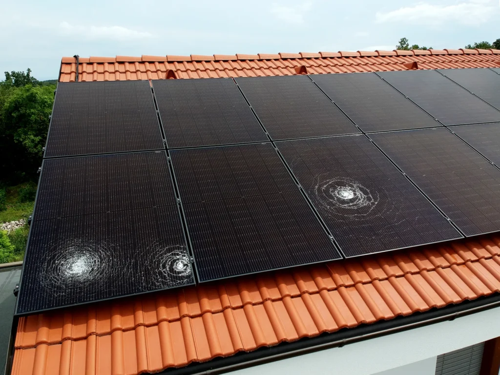 Solar panels with visible storm damage on a tile roof